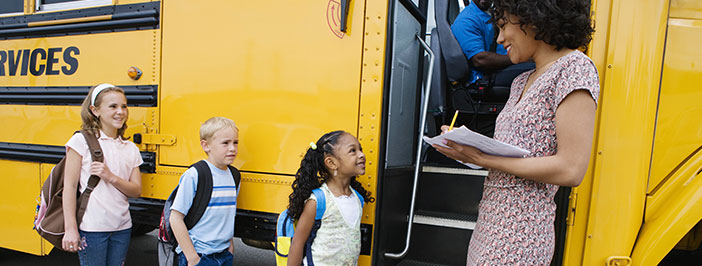 kids and teacher in front of school bus will be safer with video surveillance